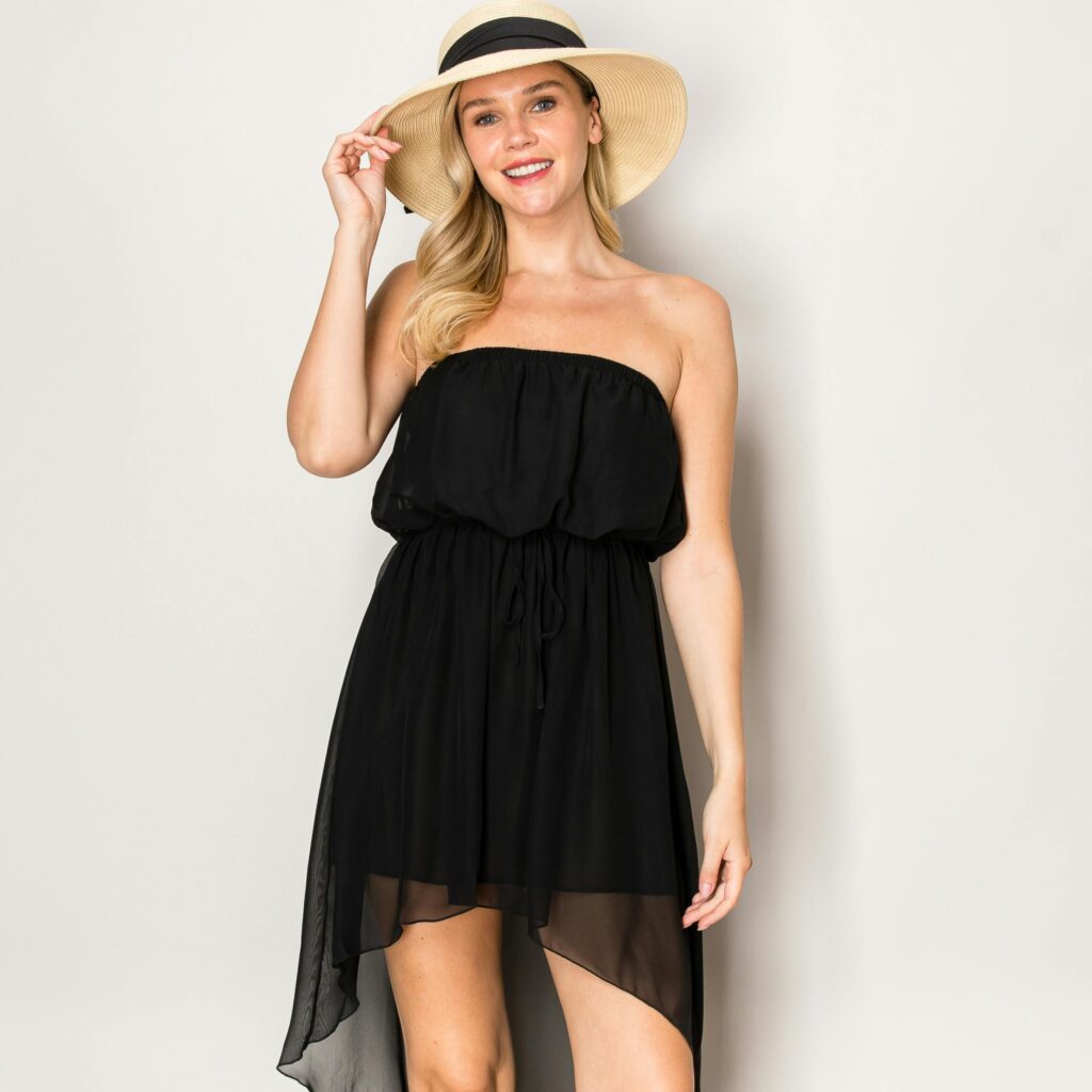 Charming woman in a black strapless dress and sun hat, exuding elegance and summer vibes.